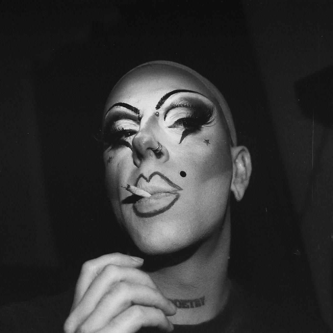 Portrait argentique d’un·e artiste drag, maquillage de scène, cigarette aux lèvres.